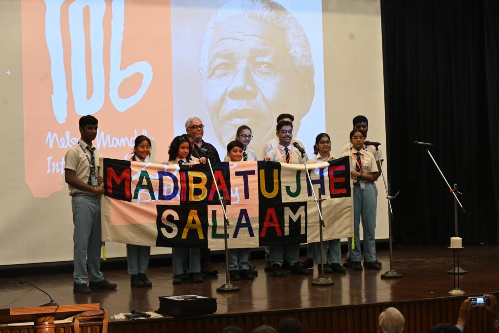 A school student choir holds up a cloth banner that reads 'Madiba Tujhe Salaam' (Madiba we salute you), created by a tribal community in Jharkhand, at the Nelson Mandela International Day 2024 event at India International Centre, New Delhi. 